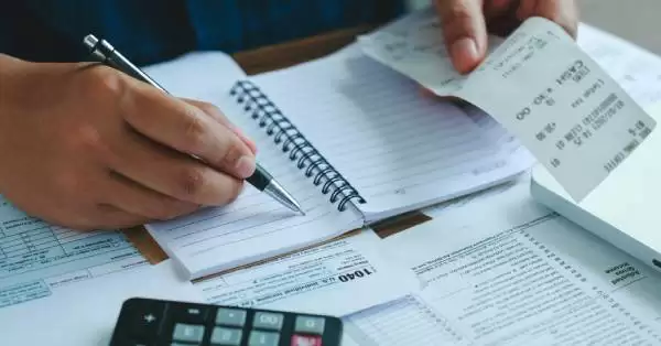 Pessoa organizando contas, simbolizando estratégias para quitar dívidas e alcançar estabilidade financeira.