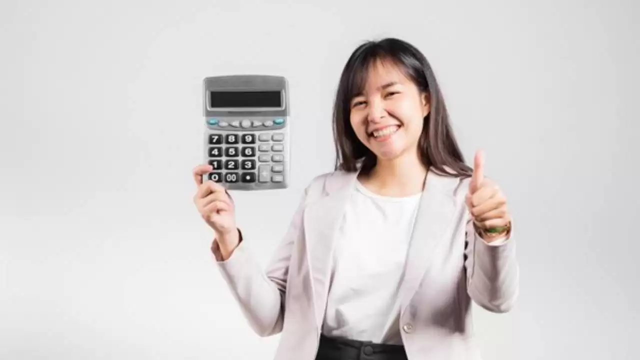 Mulher sorrindo com uma calculadora, representando sucesso financeiro após limpar o nome no Serasa.