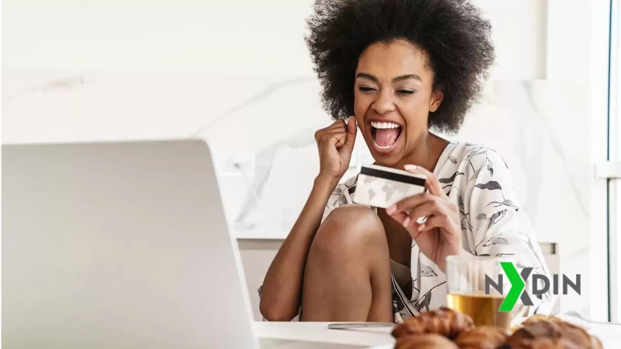 Mulher sorrindo segurando um cartão de crédito, representando a conquista de ofertas vantajosas.
